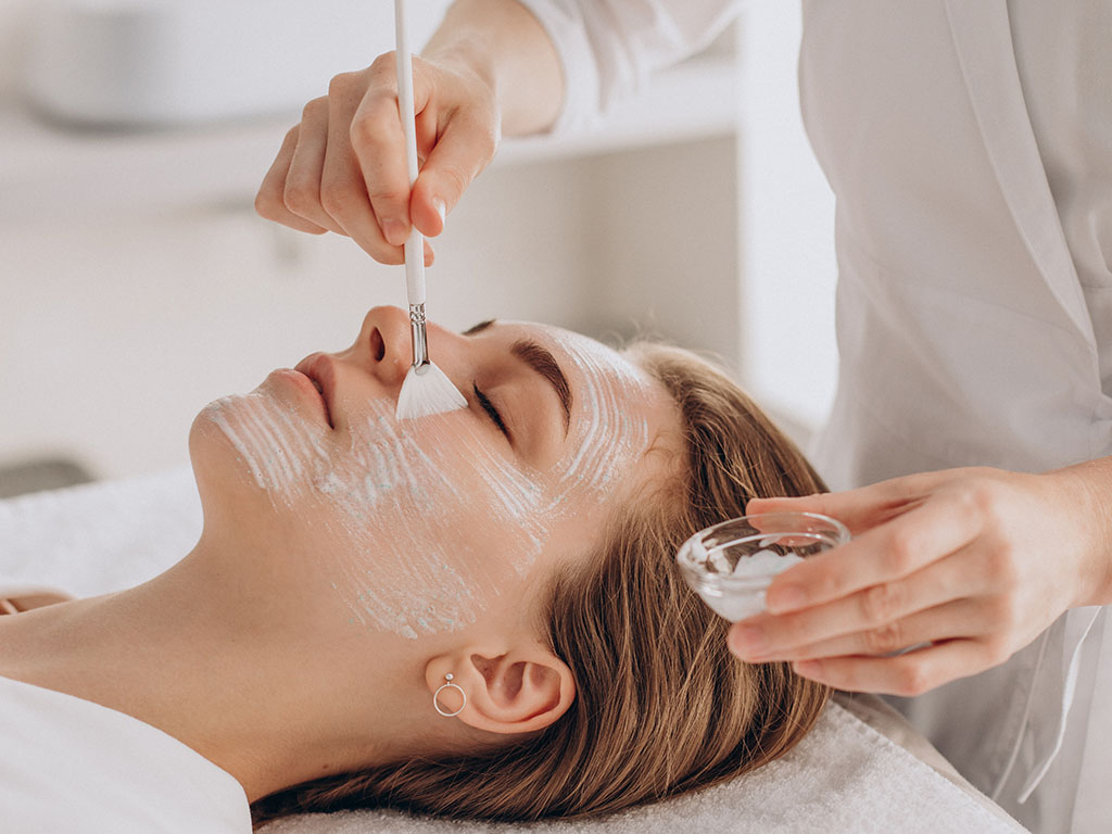 Cosmetologist doing face treatment and applying face mask